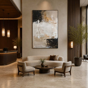 Black framed abstract painting above curved seating in a warmly lit hotel lobby.