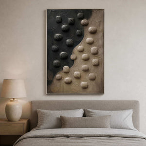 Charcoal and taupe relief canvas displayed above a quiet neutral bed.