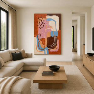 Warm abstract curves in a wood frame beside a cream sectional sofa.