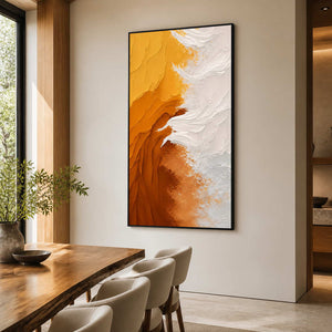 Black framed yellow and white abstract artwork beside a wooden dining table.