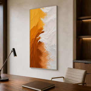 Silver framed yellow and white abstract artwork above a wooden desk in a study.