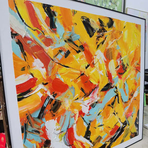 Photographed view of interlocking yellow, orange, light blue, white and black abstract strokes, with the artwork edge and surrounding background visible.
