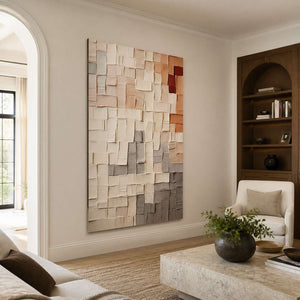 Frameless textured grid artwork beside bookshelves and cream seating in a warm living room.