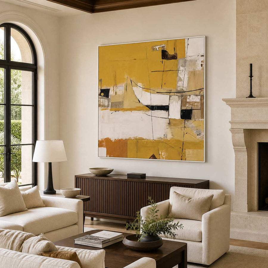 White-framed yellow abstract wall art above a wooden cabinet beside cream living room seating.