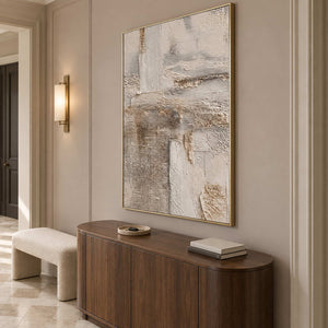 Tall neutral abstract above a rounded wooden cabinet in a paneled hallway.