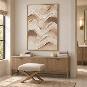 Tenderness in a gold frame above a fluted wood cabinet with towels beside a cushioned stool in a bathroom dry area.