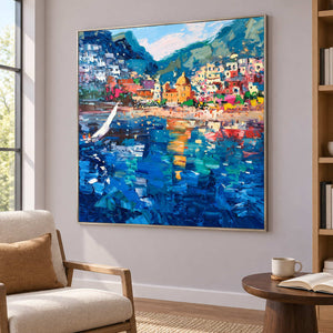 Coastal town painting beside a cream reading chair and bookshelf.