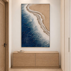 White surf curling along a sandy shore beside dark blue water in a silver frame, displayed above an entryway console.