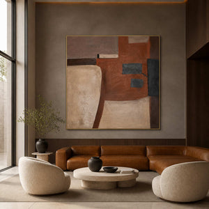 Gold framed rust and beige artwork above a leather sofa in a hotel lobby.