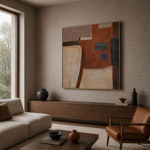 Rust and beige geometric painting in a gold frame beside living room seating.