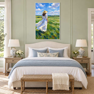 The Fields Await in a white frame above a cream bed with pale blue bedding and a woven bench against sage paneling.
