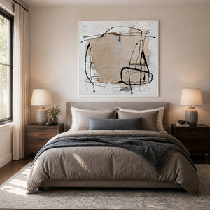 White-framed abstract wall art above a bed layered with soft neutral linens.