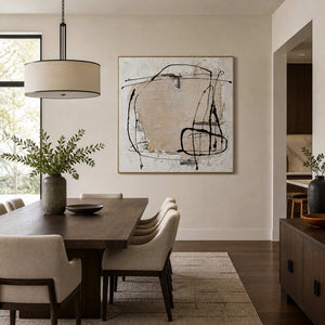Gold-framed abstract wall art displayed beside a wooden dining table and upholstered chairs.