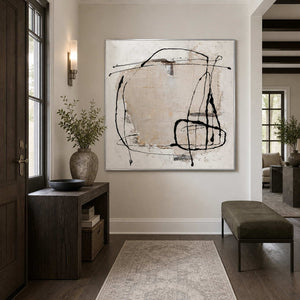 Silver-framed abstract wall art beside a wooden console and bench in an entryway.
