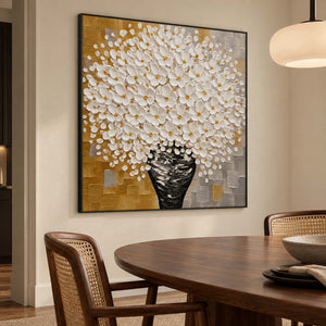 Black-framed floral artwork beside a round dark dining table and woven-back chairs.