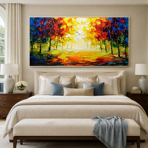 White-framed golden woodland painting above an ivory upholstered bed with blue cushions.