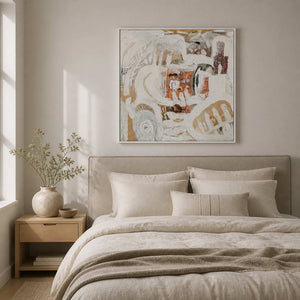 White framed textured abstract artwork above a linen bed in a softly lit bedroom.