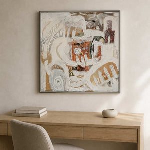 Silver framed cream and rust abstract artwork above a pale wooden home office desk.