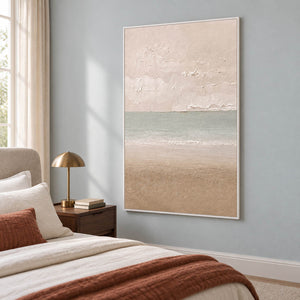 Hand-painted coastal canvas in warm ivory, sea-glass green, and sand, displayed in a bedroom in a white frame.