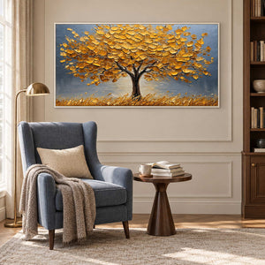 Golden leaf tree beside a blue wingback chair and a small wooden reading table.