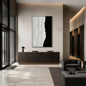 Black framed abstract artwork behind a reception desk in a tall bright hotel lobby.