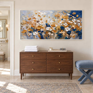 The Time to Bloom in a white frame above a wood cabinet with folded white towels beside a bathroom vanity.