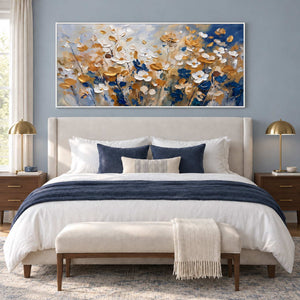 The Time to Bloom in a white frame above a cream bed with navy cushions and a blue throw against a muted blue wall.