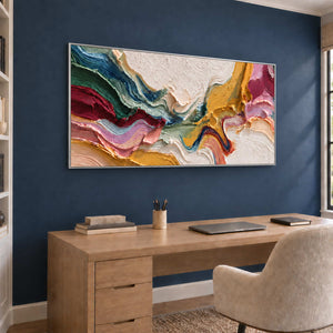 Pink and green folded abstract above a wooden desk against a navy accent wall.