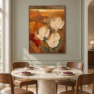 Textured cream flowers painting against an amber and rust background in a brown wood frame in a dining room.