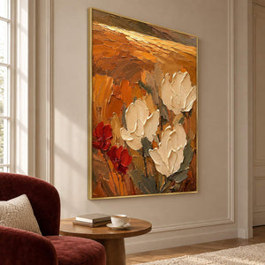Textured cream flowers painting against an amber and rust background in a gold frame in a lounge.