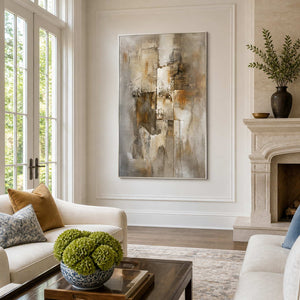 White-framed brown and cream abstract artwork between tall windows and a living room fireplace.