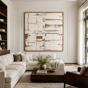 Pale layered abstract in a wood frame above a cream sectional and dark coffee table.