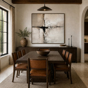 Wood framed abstract artwork above a sideboard behind a wooden dining table and leather chairs.