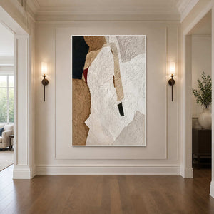 White framed textured abstract artwork between wall sconces in a warm hallway with wooden flooring.