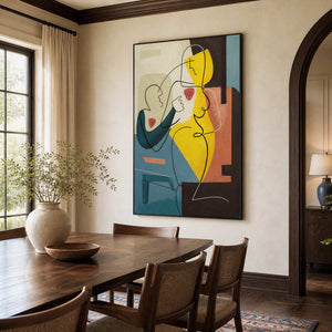 Black-framed colorful figures beside a wooden dining table and cane-backed chairs beneath dark ceiling beams.