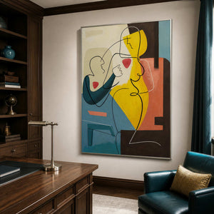 Silver-framed figurative painting with yellow and teal shapes beside a wooden desk and deep teal study chair.