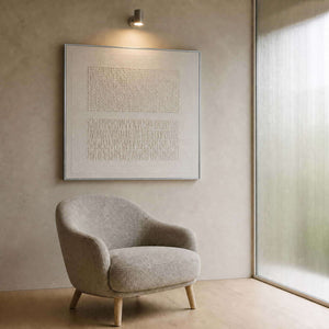 Ivory relief canvas beside a soft chair in a quiet sitting nook.