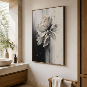 Wood framed monochrome floral artwork beside a stone bathroom basin and towels.
