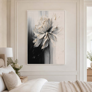 White framed textured floral artwork beside a softly layered cream bed.