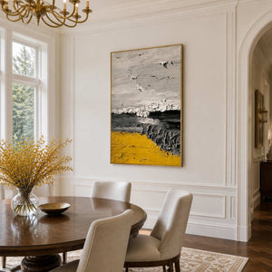 Gold framed textured abstract artwork beside a round wooden dining table and cream chairs.