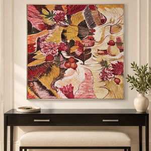 Red flowers and rounded fruit forms woven through ochre, cream and dark bands in an artwork with a silver-colored frame, displayed in an entryway above a console or bench.