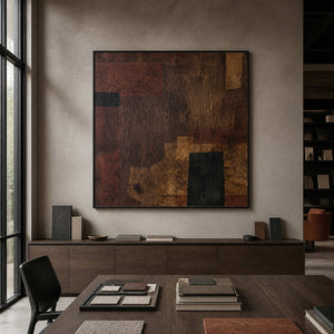 Black framed textured abstract painting displayed above material samples in an architectural studio.