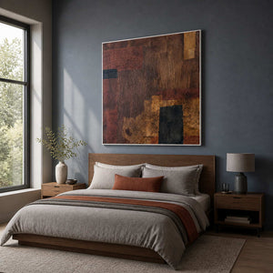 Earth toned square painting in a white frame above a wooden bedroom headboard.