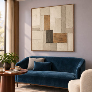 Textured ivory stone caramel and charcoal blocks in a quiet square composition, displayed in a hotel lounge in a brown wood frame.