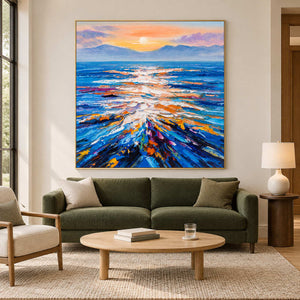 Warm-sky seascape over an olive sofa with a round wooden coffee table.