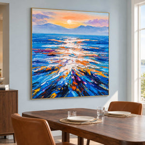 Sunlit sea artwork on a pale blue wall beside a wooden dining table and brown chairs.