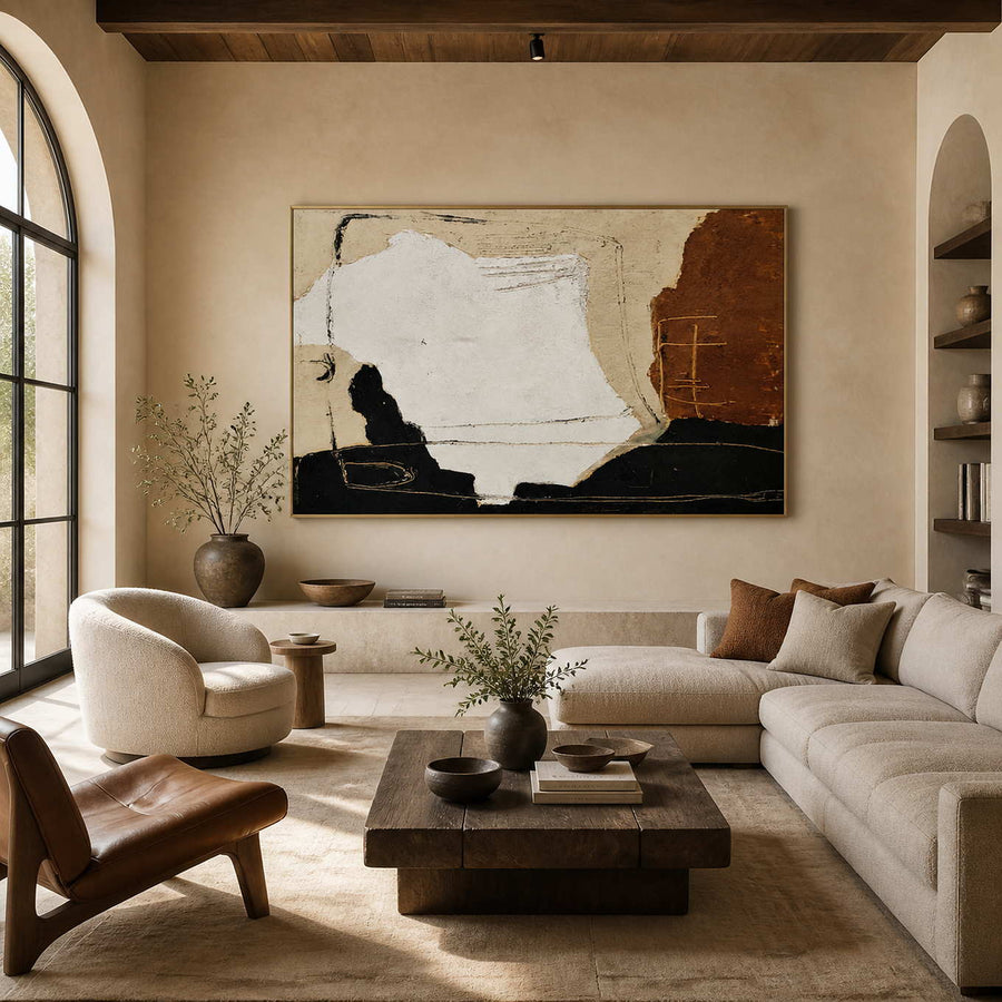 Warmth Goes with You in a gold frame above a cream sofa, with white, rust, and black shapes in a warm living room.