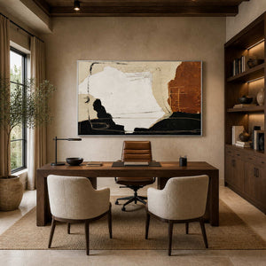 Silver-framed horizontal abstract painting behind a wood desk with cream guest chairs in a home office.