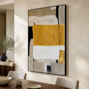 Black framed ochre abstract artwork above a wooden dining table.