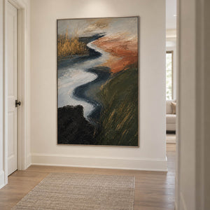 A winding pale waterway between dark green and rust-colored fields in a silver frame, displayed in a hallway.